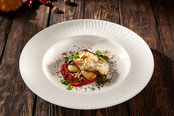 istock Baked eggplant roll with cheese and tomatoes, elegantly plated on a white dish 1871989334