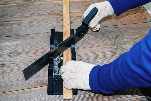 the foreman cuts the baseboard with equipment for cutting at precise angles with a hand saw