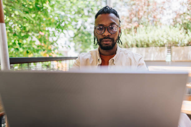 istock Mid adult man working using laptop at coffee shop 1872010763