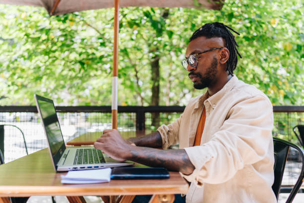 istock Mid adult man working using laptop at coffee shop 1872010777