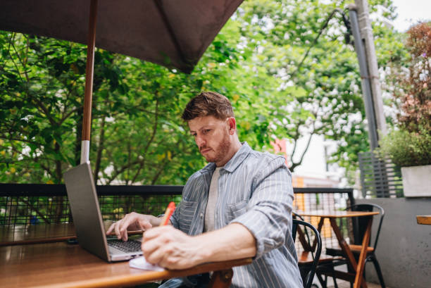 istock Mature man working using a laptop at coffee shop 1872011883