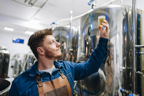 istock Quality controller mature man analyzing a glass of beer at brewery 1872015057