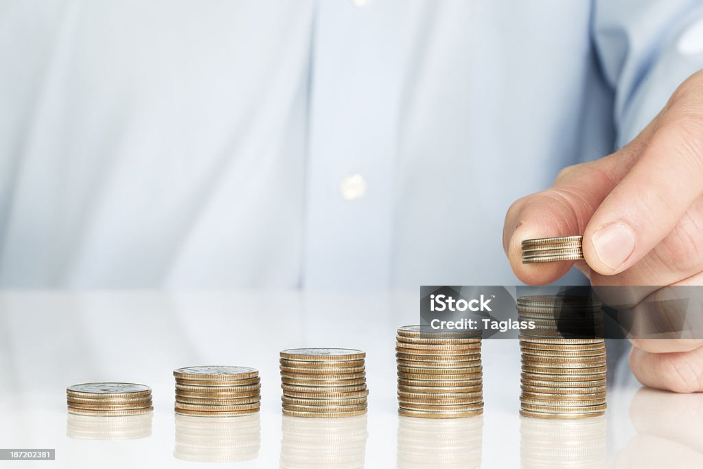 Man stacking coins man in blue shirt saving coins. Compound Interest Stock Photo