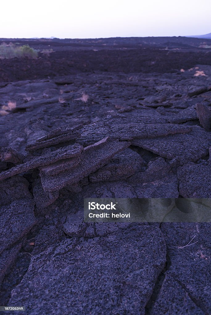A dried, black, cracked lava field.  Black lava field from the volcano Erta Ale mountain.  Early morning before sunrise. Petrified lava.  Afar region, Ethiopia. Afar Triangle Stock Photo