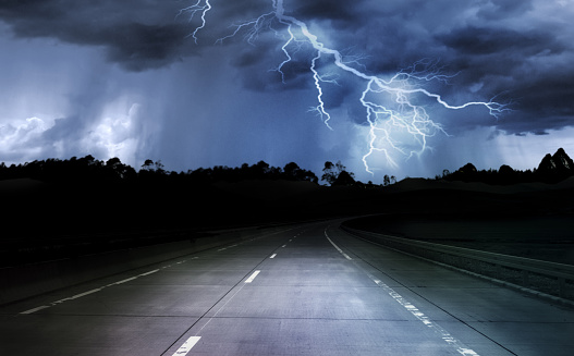 dark night road through forest and mountains, rain and storm with lightning