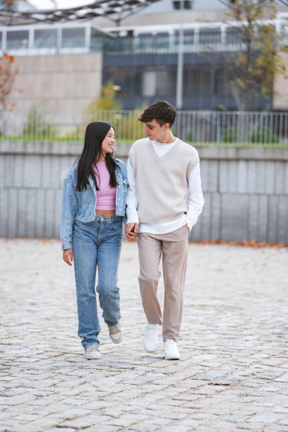 istock Young couple holding hands while walking outdoors. 1872065200