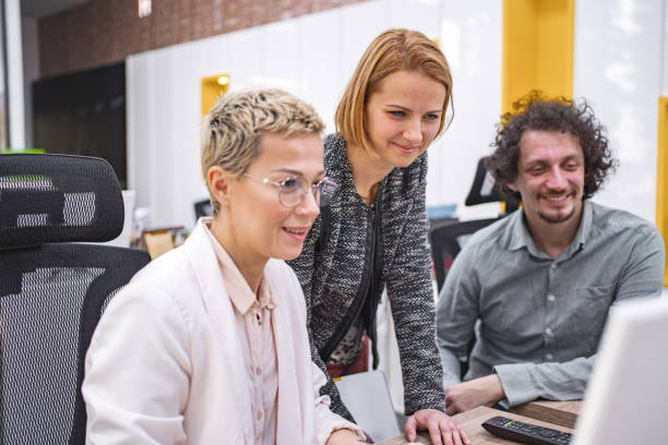 istock Three coworkers working together on a computer at the office 1872065724