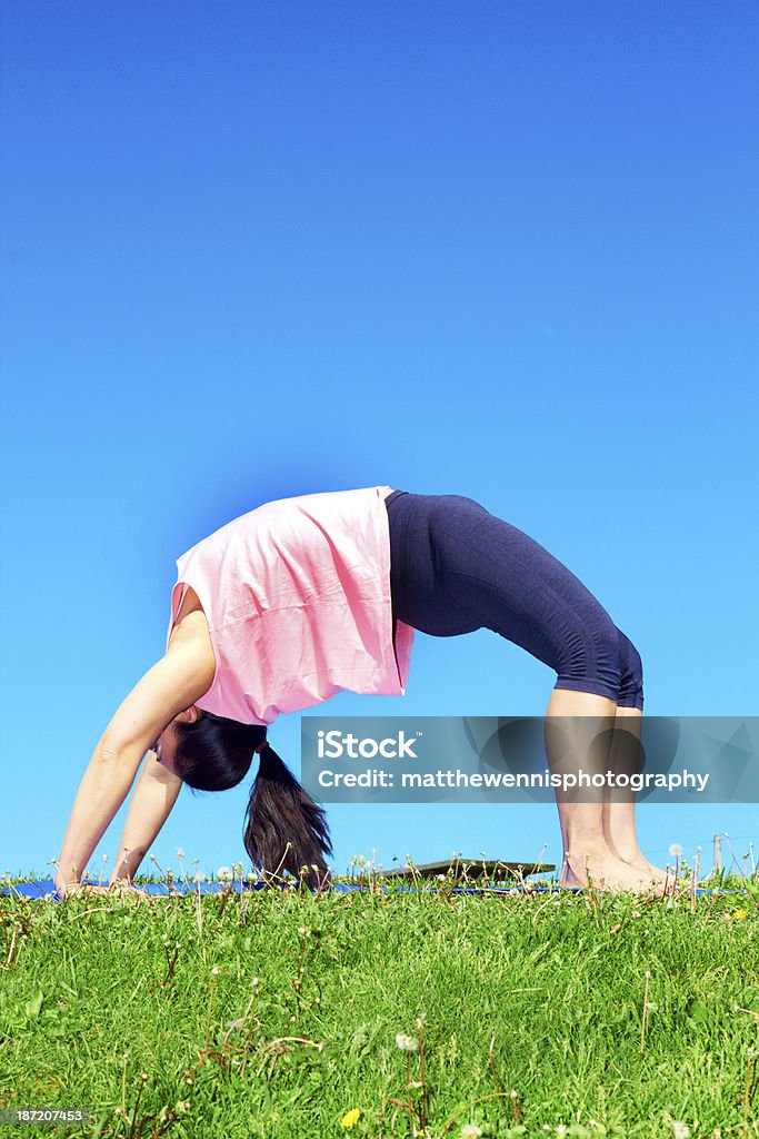 Young Beautiful Mixed Race Woman Doing Yoga young beautiful mixed race girl doing yoga on a beautiful day with clear blue sky. Pretty asian female performing relaxation exercise on a nice spring day. Color image, copy space. Active Lifestyle Stock Photo