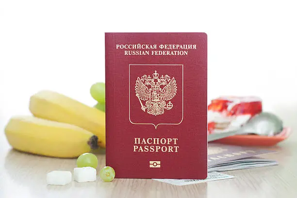 Russian international passport is used in travels, front view. Banana and cake on background.