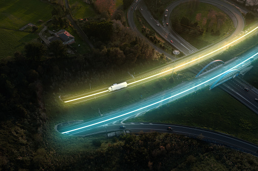 Aerial view of a highway with blue and yellow neon lights lightening the asphalt