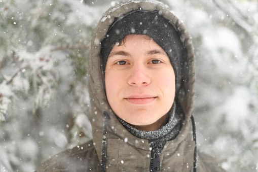 Close-up portrait of young beautiful girl wearing scarf while snowing outdoor.