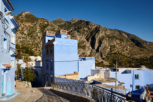 City street with blue houses and mountains in the background in Chefchaouen, Morocco, Africa.