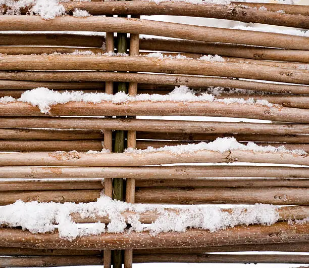 close-up wicker wooden fence with parts of snow