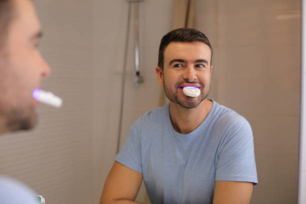istock Man whitening  his teeth at home 1872159083