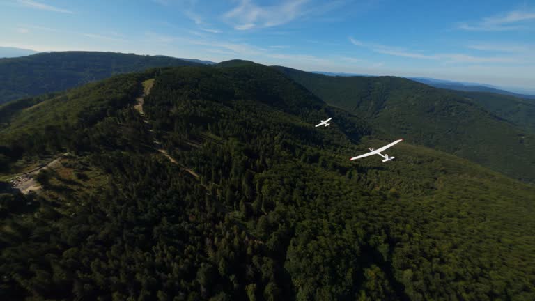 Airplane gliders flying above forests and hills