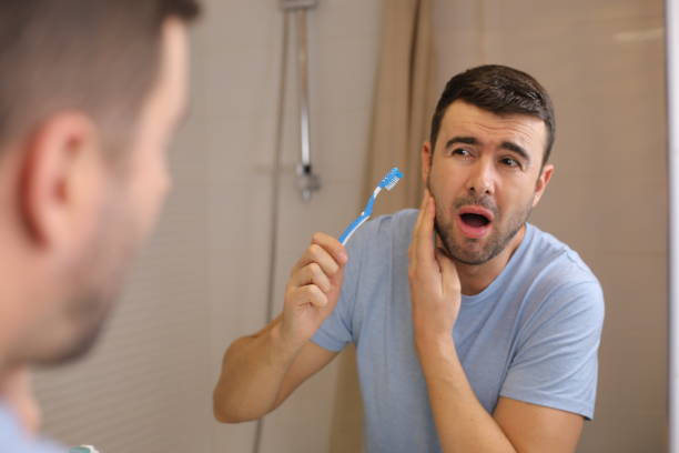 man experimenting pain while brushing his teeth - brushing teeth healthcare and medicine cleaning distraught стоковые фото и изображения