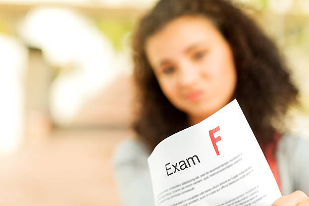 Female student showing exam result with F grade on college campus. Horizontal shot.