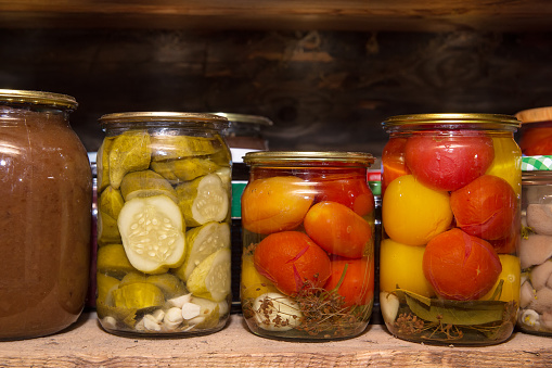 Glass jars of canned vegetables are on the shelf.