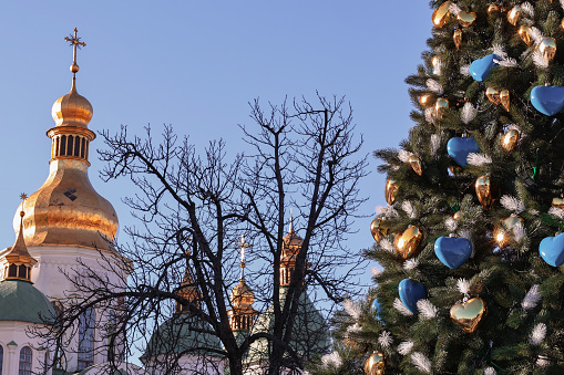 Kyiv, Ukraine - December 20, 2023: a New Year's tree with a Ukrainian trident on top was put up on Sofiyivska Square in Kyiv. A flag of Ukraine was placed nearby.