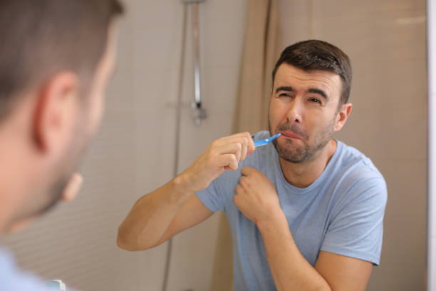 мужчина экспериментирует с болью во время чистки зубов - brushing teeth healthcare and medicine cleaning distraught стоковые фото и изображения