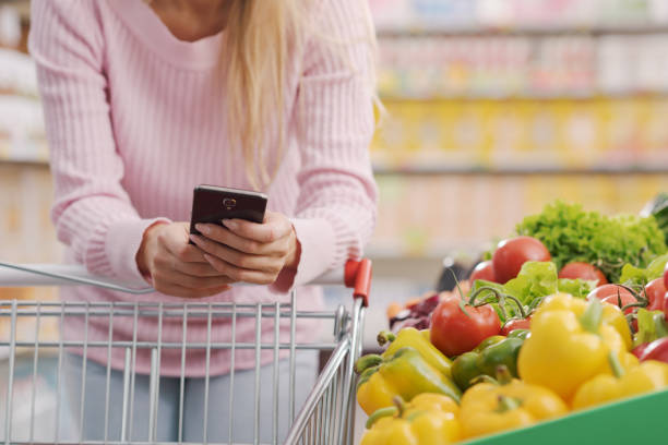 istock Woman buying fresh vegetables and using her smartphone 1872179995