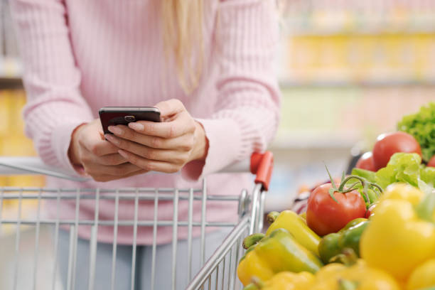 istock Woman buying fresh vegetables and using her smartphone 1872183640