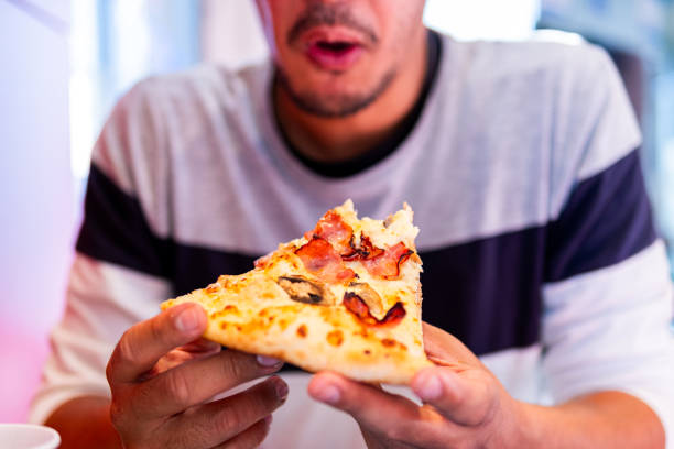 istock Unidentified person relishes fresh, hot pizza. 1872185187