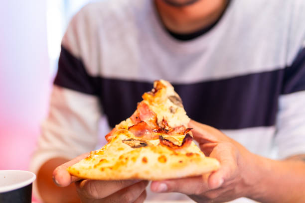 istock An unrecognizable gentleman enjoys piping-hot pizza. 1872185188
