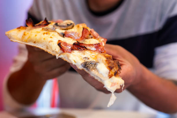 istock Faceless guest relishing delicious, pizza slice. 1872185712