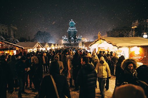 Illuminated town square full of people, Christmas market named Wiener Christkindlmarkt on the Karlsplatz at night