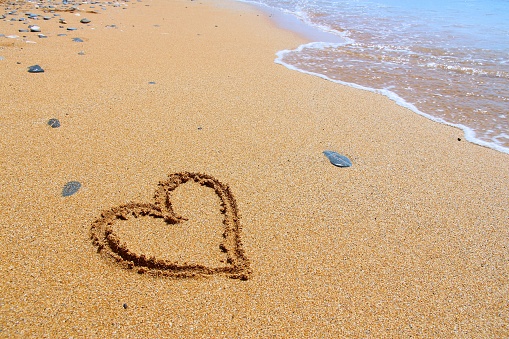 Finger drawing on a sandy beach in Crete, Greece - heart shape, symbol of love.
