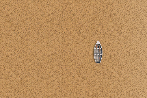 An overhead view of a small boat marooned on parched, cracked soil, symbolizing severe drought and water scarcity issues.
