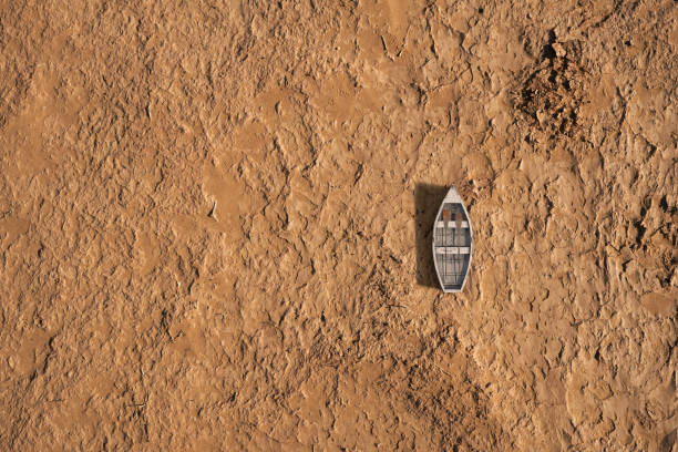 An overhead view of a small boat marooned on parched, cracked soil, symbolizing severe drought and water scarcity issues.