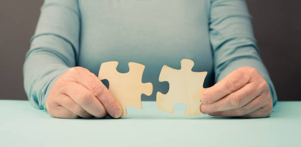 istock Holding two pieces of a puzzle in the hands, connecting together as a team, solving a problem, strategy and communication concept 1872218620