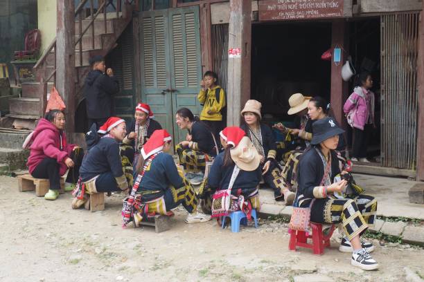 donne e bambini della tribù red dao seduti su sgabelli che tessono tessuti tradizionali nel villaggio di ta phin nel vietnam settentrionale - vietnam vietnamese culture vietnamese ethnicity north vietnam foto e immagini stock