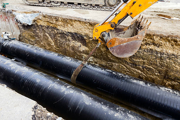 Power of bagger Excavator holds pipeline above the trench during the welding procedure. bagger stock pictures, royalty-free photos & images