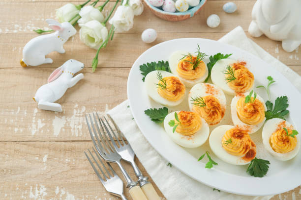 istock Easter stuffed eggs. Traditional Easter brunch or dinner with stuffed eggs with paprika, carrot cake bars and chocolate nest cakes with glazed eggs. Easter meal dishes with holday decorations Top view 1872245571