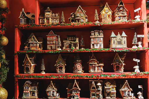 Illuminated Christmas market stall with wooden souvenirs in shape of houses and displayed on shelves, Wiener Christkindlmarkt at night