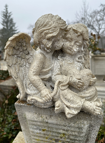 Two angel figurine on a tombstone in the public cemetery