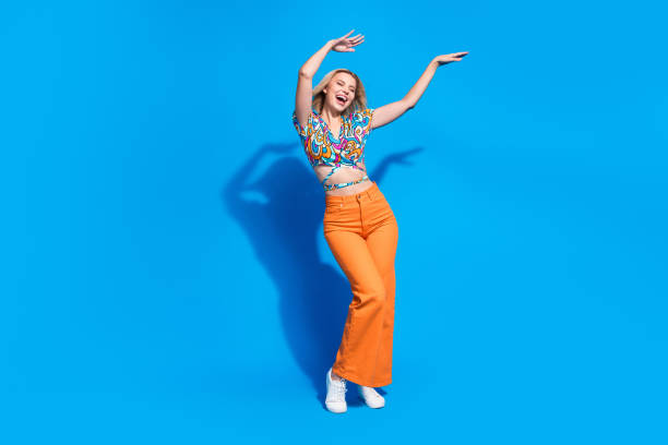 Full size photo of relaxed positive gorgeous girl wear stylish shirt hold hands up dancing isolated on vivid blue color background stock photo