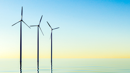 Offshore Wind Turbines At Sunset. Panoramic view of wind farm or park, with high wind turbines for generation electricity. wind turbines at sea. copy space