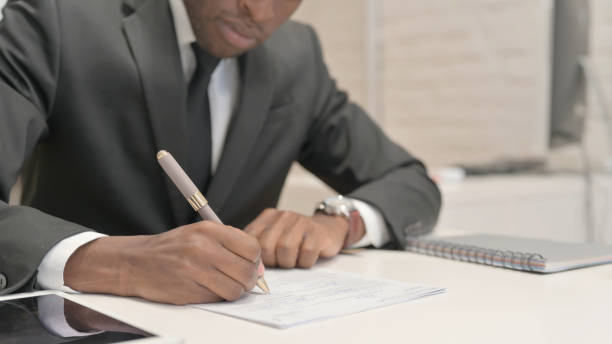 istock Close Up of African Businessman Writing Documents 1872288214