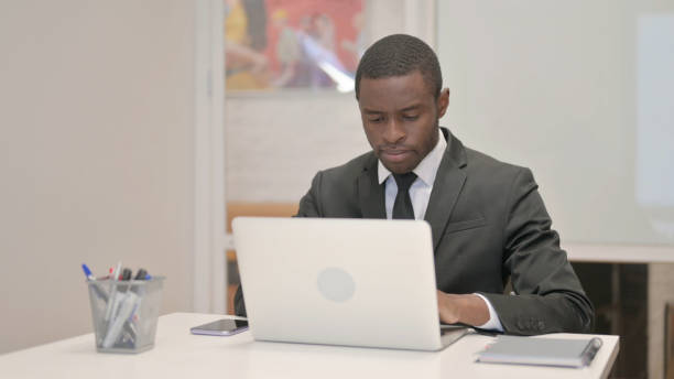 istock African Businessman Working on Laptop while Sitting in Office 1872288770