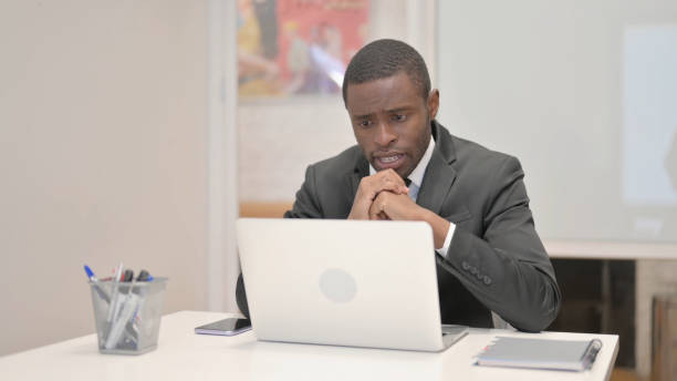 istock African Businessman Chatting Online on Laptop while Sitting in Office 1872290432