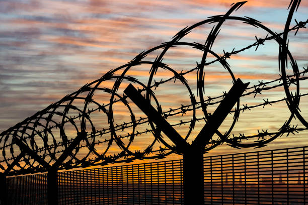 istock Barbed Wire Security Fence Against Sunset Sky 1872296415