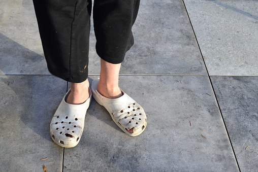 Close-up on a white man who still uses cleaned worn rubber slippers footwear for indoor or outdoor use  that still fulfills its functions 100 procent.