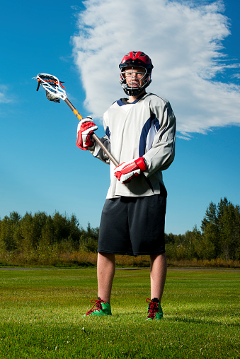 A field lacrosse player standing in a field holding his stick