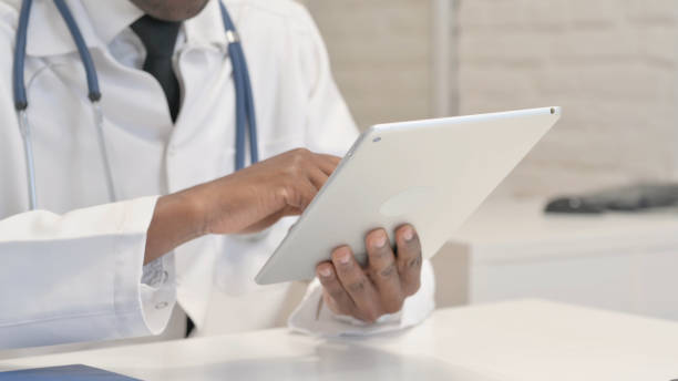 istock Close up of African Doctor Browsing Internet on Tablet 1872331988