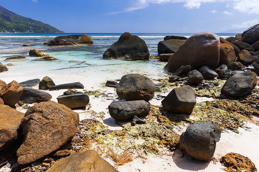 Coastal stones lay on white sands of Beau Vallon beach, Seychelles. Natural landscape photo taken on a sunny summer day