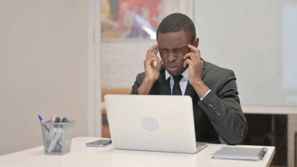 istock African Businessman having Headache while Working on Laptop in Office 1872342779